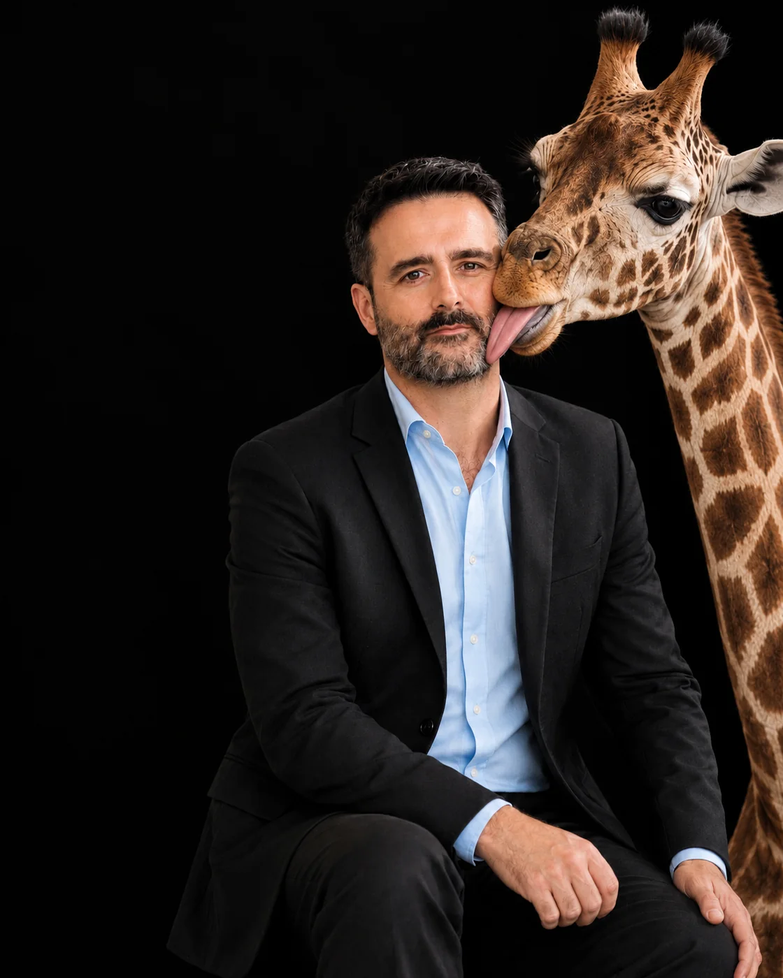 Andrés Cardenete Montiel, periodista, escritor y cofundador de Jirafas, mientras una jirafa le lame la mejilla
